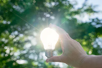 Hand h&auml;lt LED-Lampe gegen die Sonne