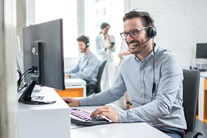 Mann mit Kopfh&ouml;rern vor einem Computer